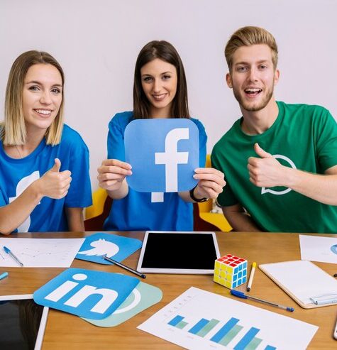 smiling-woman-holding-facebook-logo-with-his-friends-showing